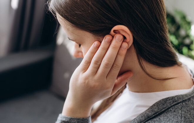 Junge Frau hält sich ihr Ohr zu.