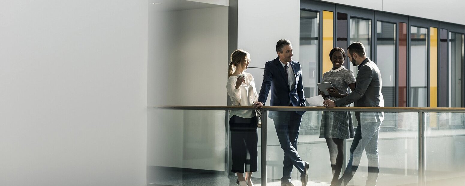 Vier Businessleute unterhalten sich im Flur eines Unternehmens.