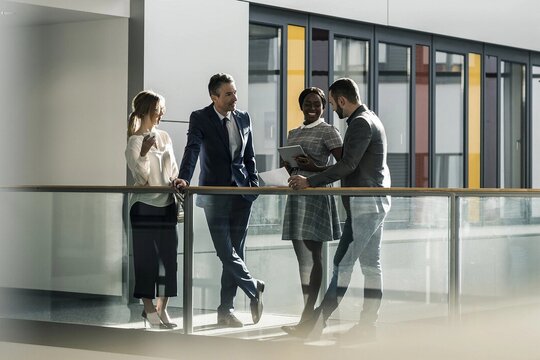Vier Businessleute unterhalten sich im Flur eines Unternehmens.
