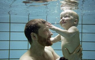 Mann mit Baby beim schwimmen