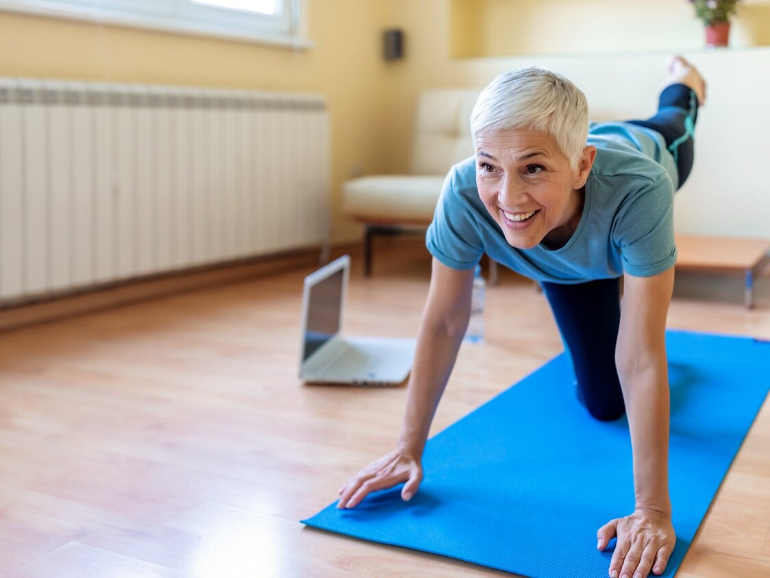 Eine Frau macht auf einer Matte eine Yoga-Übung.