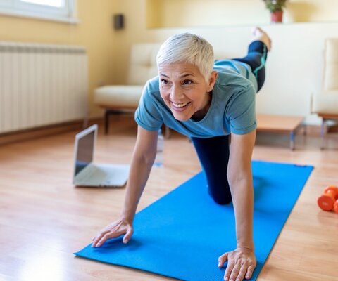 Eine Frau macht auf einer Matte eine Yoga-Übung.