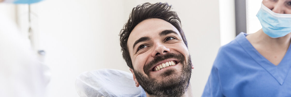 Lächelnder männlicher Patient mit weiblichen Zahnärzten in einer medizinischen Klinik.