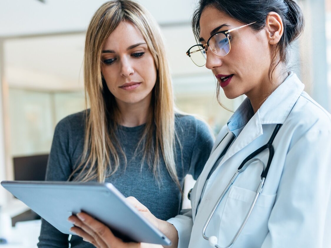 Patientin und Ärztin im Gespräch in einem lichtdurchfluteten Zimmer