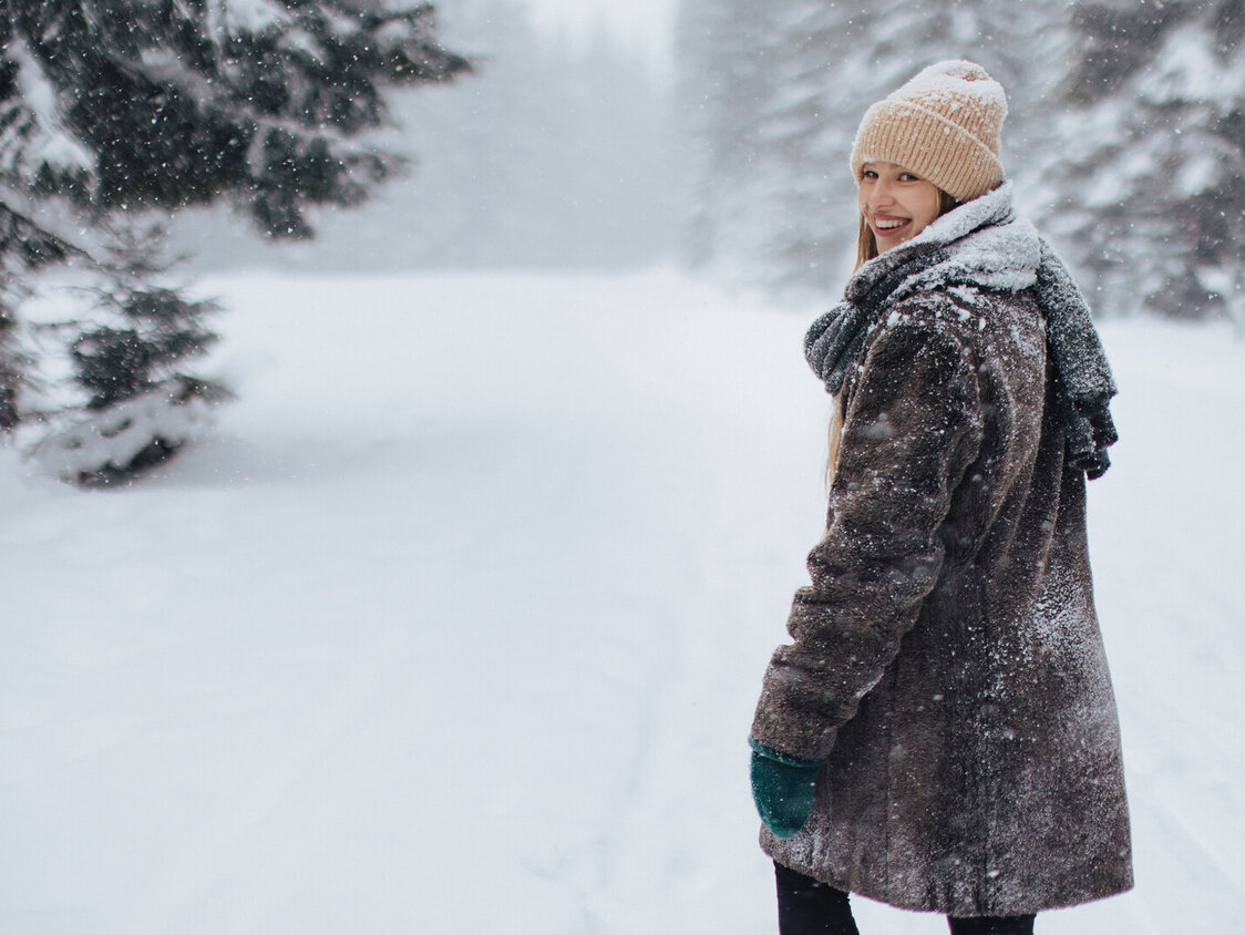 Eine Frau macht im schneebedeckten Wald einen Spaziergang.