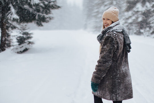 Eine Frau macht im schneebedeckten Wald einen Spaziergang.