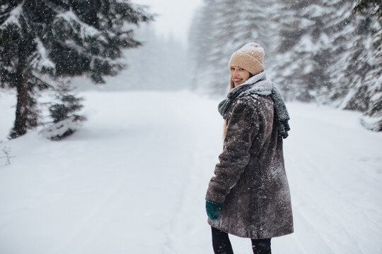 Eine Frau macht im schneebedeckten Wald einen Spaziergang.
