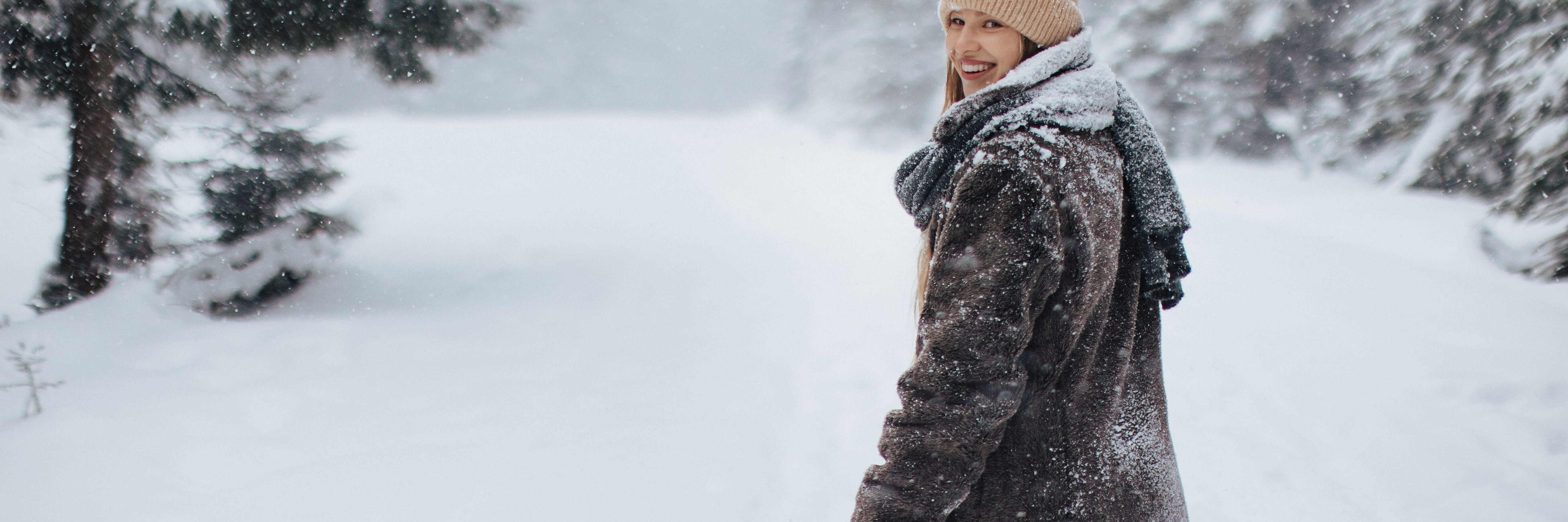 Eine Frau macht im schneebedeckten Wald einen Spaziergang.