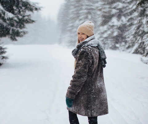 Eine Frau macht im schneebedeckten Wald einen Spaziergang.