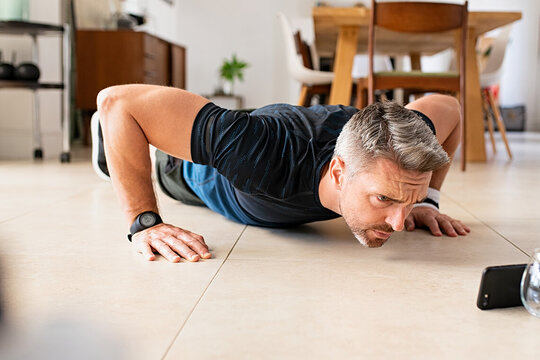 Mature,Man,Practicing,Pushups,Exercise,While,Watching,Video,On,Smartphone