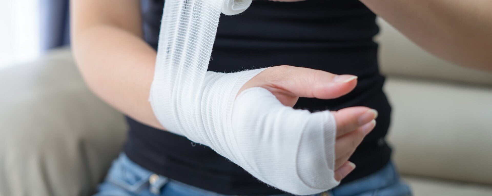 Eine Frau wickelt ihre Hand und Arm in einen Verband ein.