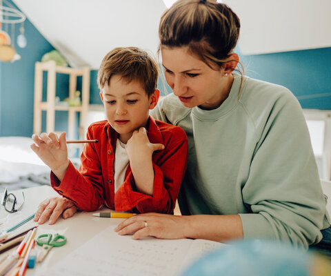 Ein kleiner Junge wird von seiner Mutter zuhause unterrichtet. 