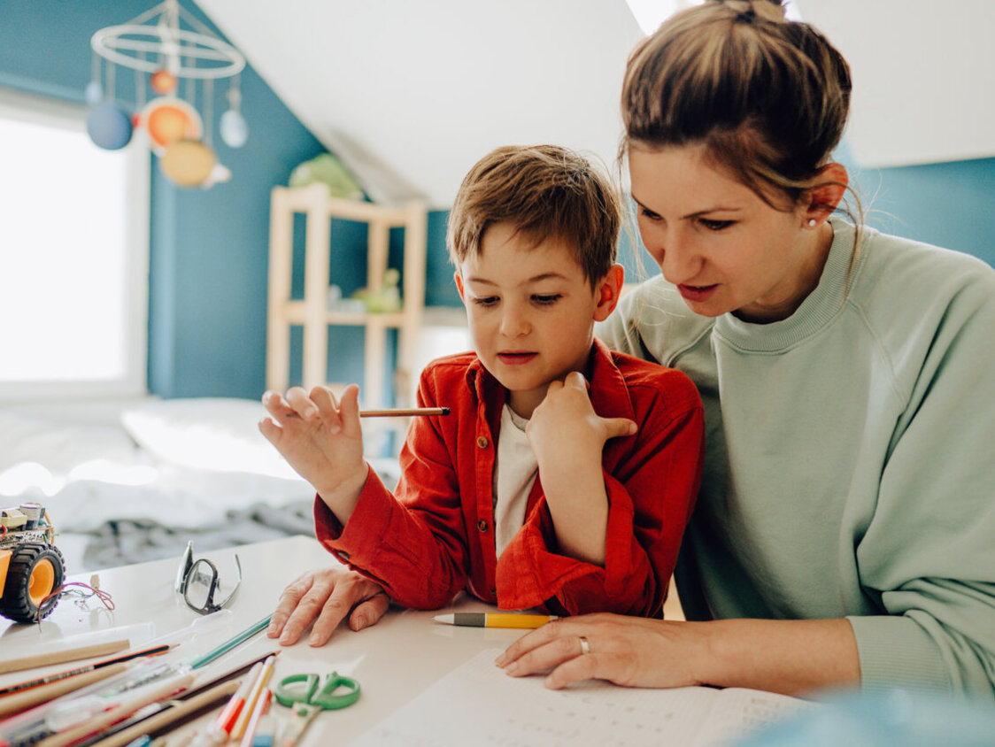 Ein kleiner Junge wird von seiner Mutter zuhause unterrichtet. 