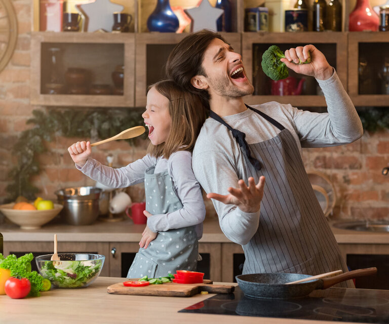 Ein Mann und eine Frau stehen in der Küche und singen und tanzen.