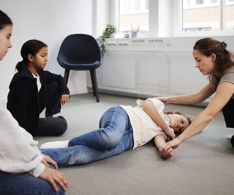 Lehrerin zeigt Kindern die Stabile Seitenlage