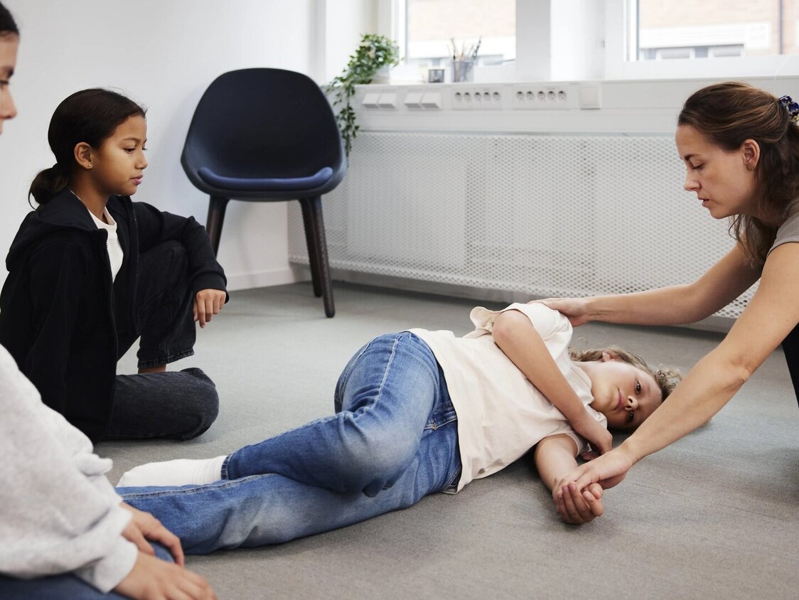 Lehrerin zeigt Kindern die Stabile Seitenlage