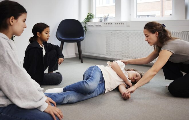 Lehrerin zeigt Kindern die Stabile Seitenlage