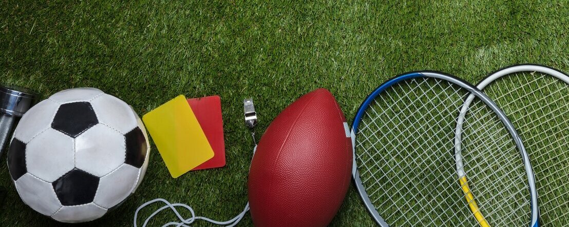 Verschiedene Sportgeräte und Bälle liegen auf dem Rasen.