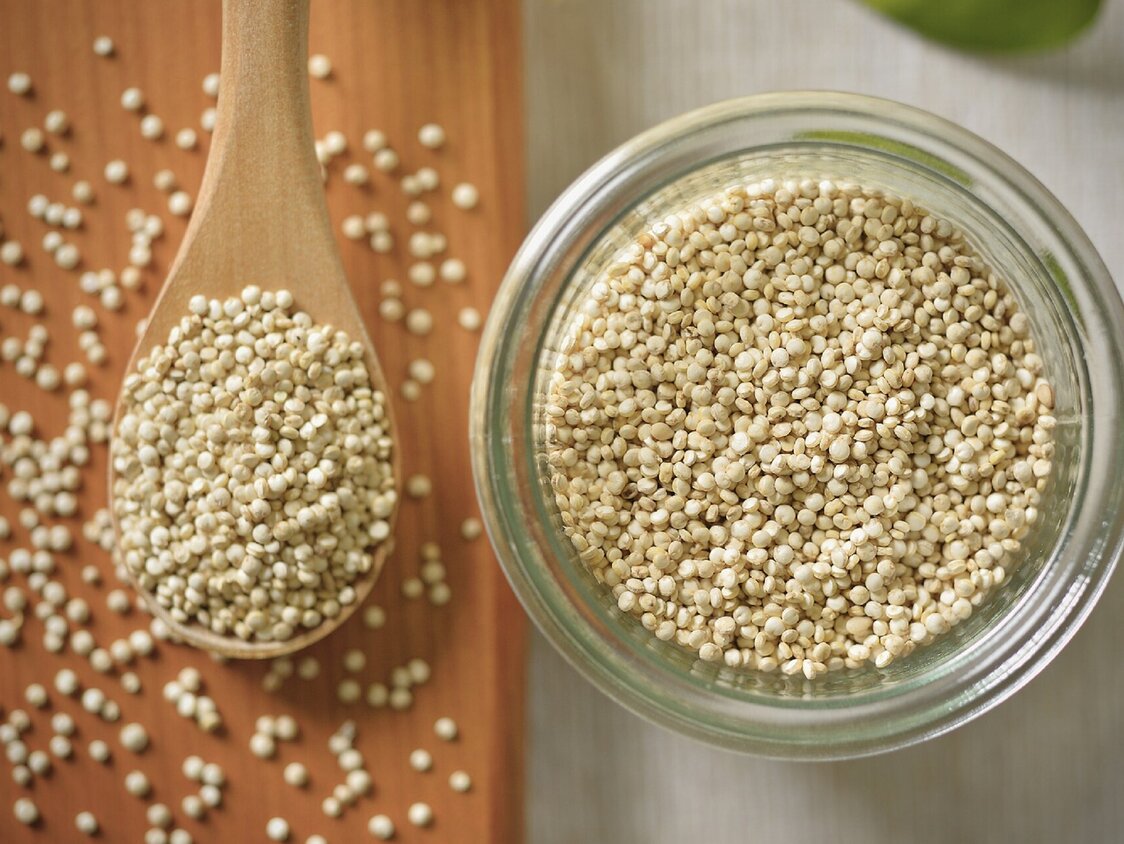Quinoa in einer Glasschale und auf einem Holzlöffel.