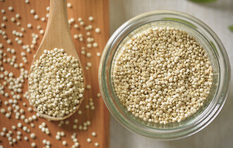 Quinoa in einer Glasschale und auf einem Holzlöffel.