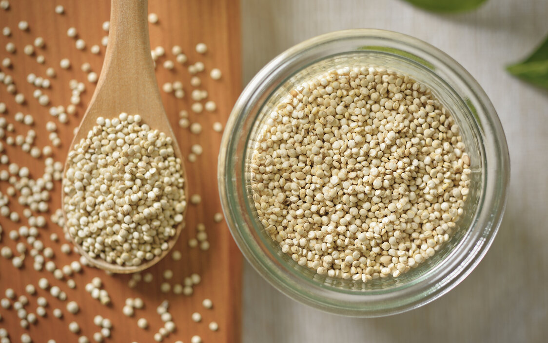 Quinoa in einer Glasschale und auf einem Holzlöffel.