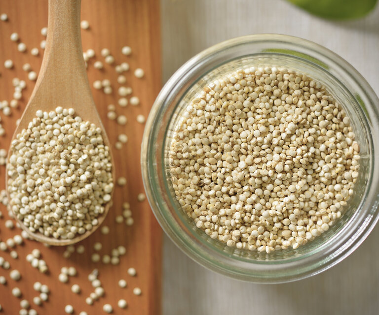 Quinoa in einer Glasschale und auf einem Holzlöffel.