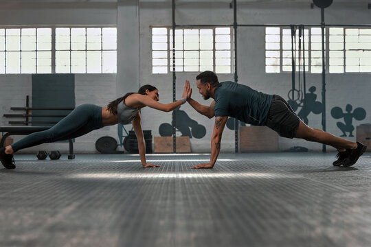 240105_hkk_dock_artikelseite_mann_frau_sportlich_zusammen_gettyimages-1415178374 Fitness-Partner, die zusammen trainieren und Liegestütze machen, High Five im Fitnessstudio. Ein fitter und aktiver Mann und eine Frau trainieren in einer Gesundheitseinrichtung als Teil ihrer Trainingsroutine. Ein Paar bei einer Übung