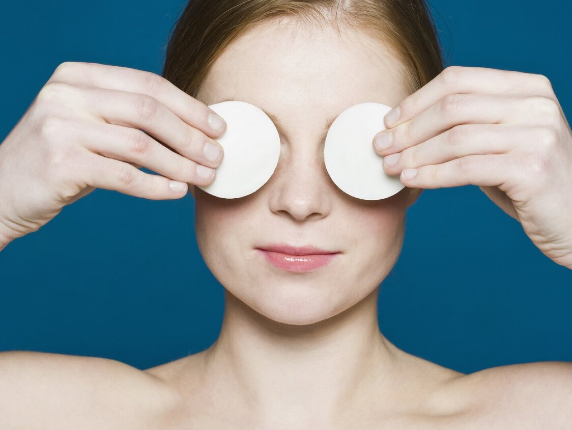 Eine Person legt sich zwei Wattepads auf die Augen.
