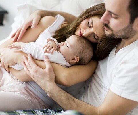 baby schlaeft im arm von mutter und vater