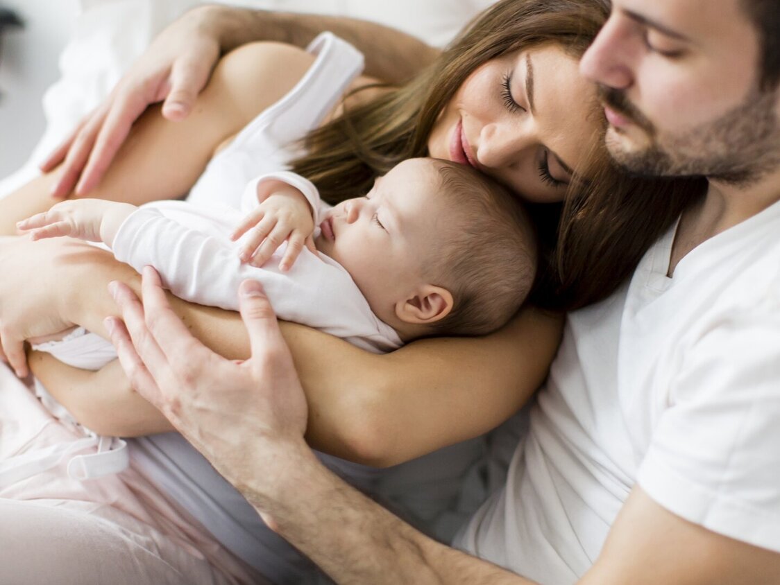 baby schlaeft im arm von mutter und vater