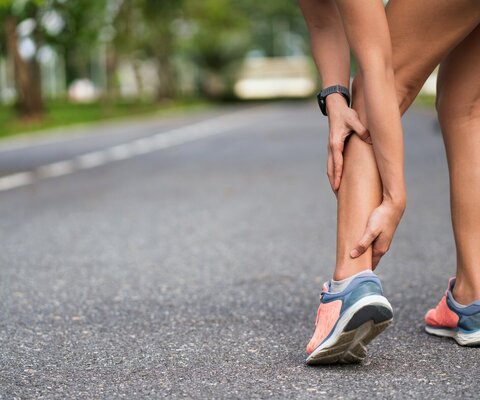 Frau hält ihre Achillessehne mit den Händen fest und leiden unter Schmerzen. 