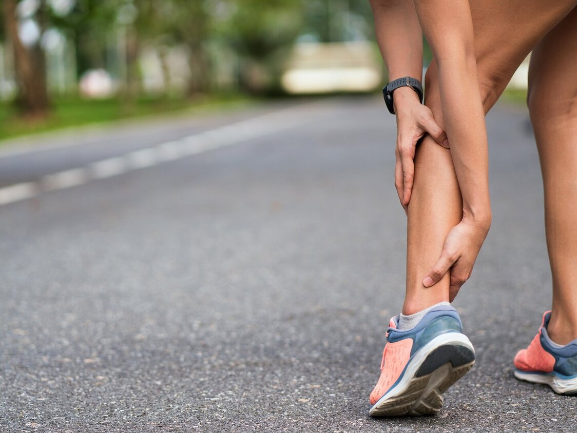 Frau hält ihre Achillessehne mit den Händen fest und leiden unter Schmerzen. 