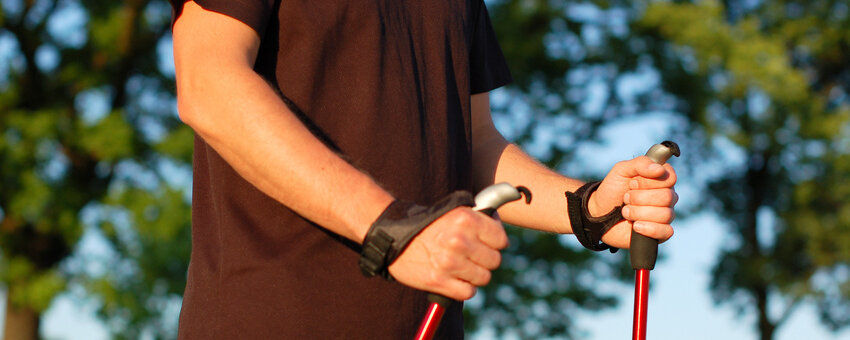 Arme und Oberkörper eines Mannes, der Nordic Walking Stöcker hält.