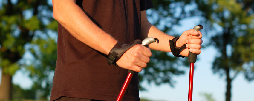 Arme und Oberkörper eines Mannes, der Nordic Walking Stöcker hält.