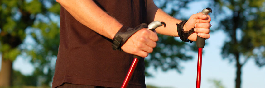 Arme und Oberkörper eines Mannes, der Nordic Walking Stöcker hält.