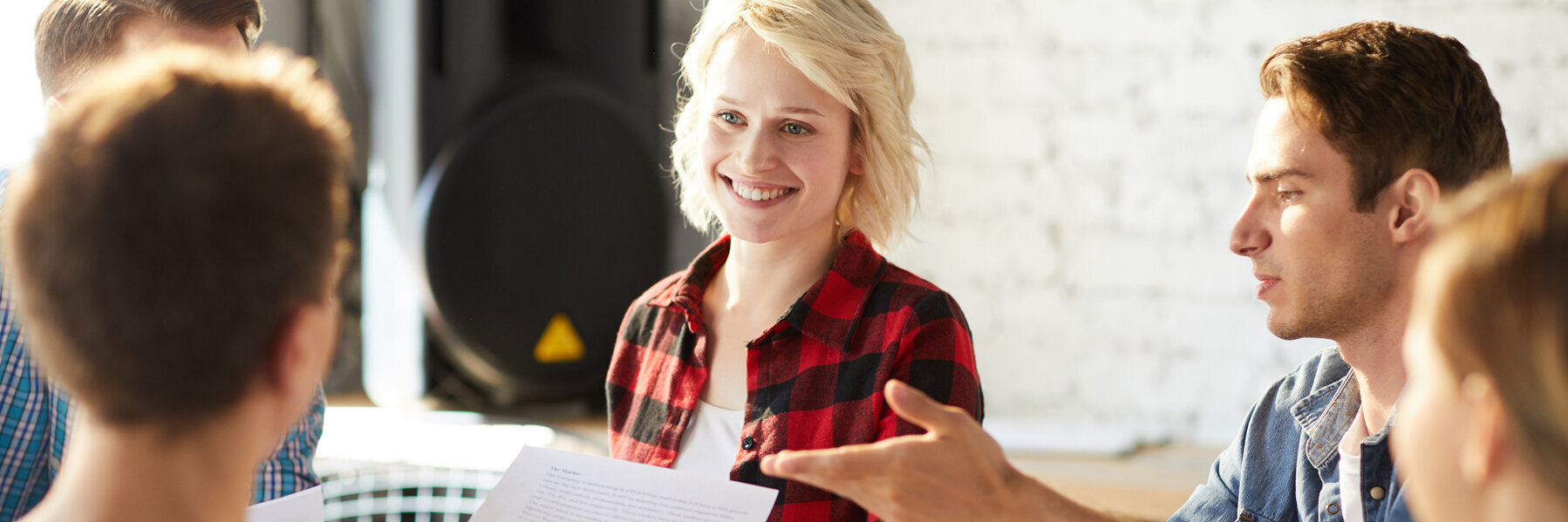 Drei Männer und zwei Frauen sitzen im Büro an einem Tisch zusammen und diskutieren Ideen.