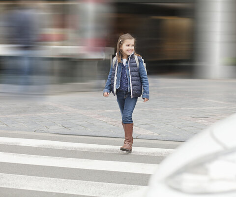 Ein kleines Mädchen läuft über einen Zebrastreifen.