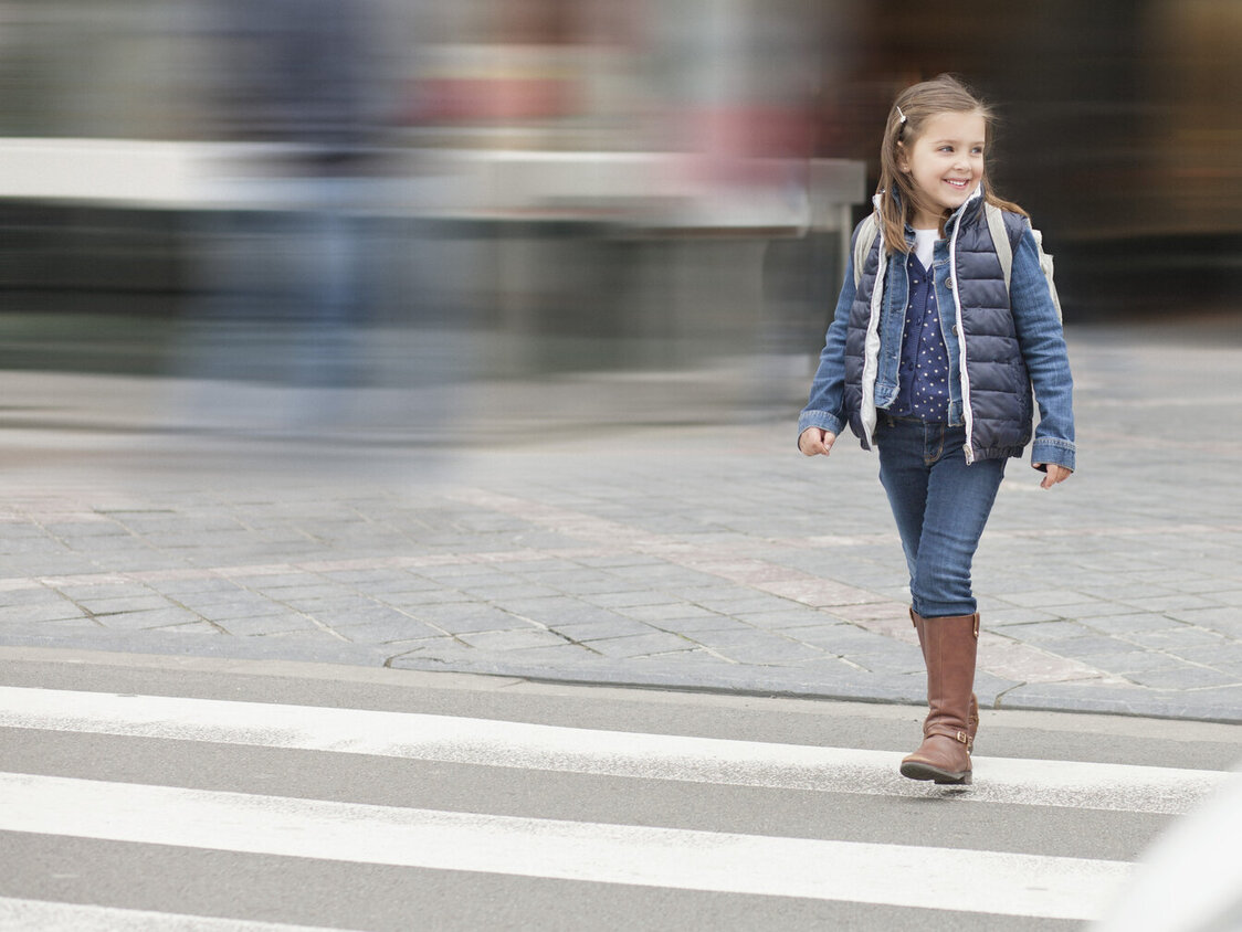 Ein kleines Mädchen läuft über einen Zebrastreifen.