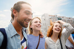 Studentengruppe (ein Mann und zwei Frauen) lachend in der Stadt
