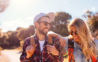 Junges Paar mit Sonnenbrillen und Rucksäcken im Urlaub.