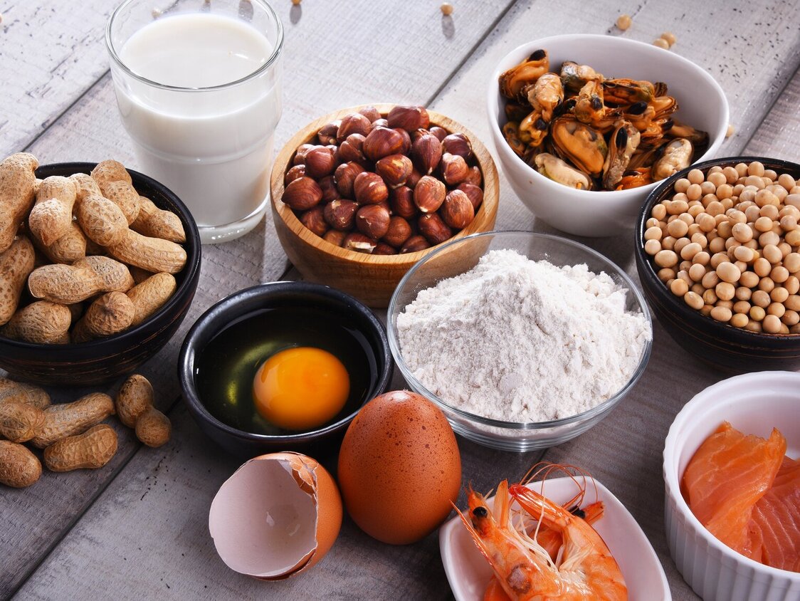 In Schalen sind Nahrungsmittel, wie Nüsse, Mehl, Eier und Lachs abgebildet.