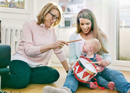Oma, Mutter und Tochter sitzen auf dem Boden und trommeln.
