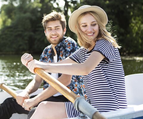 Ein Paar sitzt in einem Boot und rudert auf einem See.