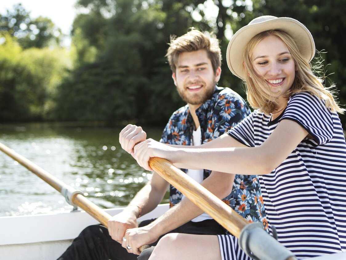 Ein Paar sitzt in einem Boot und rudert auf einem See.