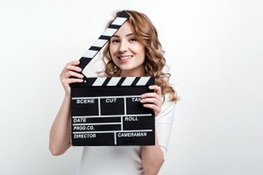 Pretty girl with a movie board on a white background Eine Frau hält eine Filmklappe in den Händen.
