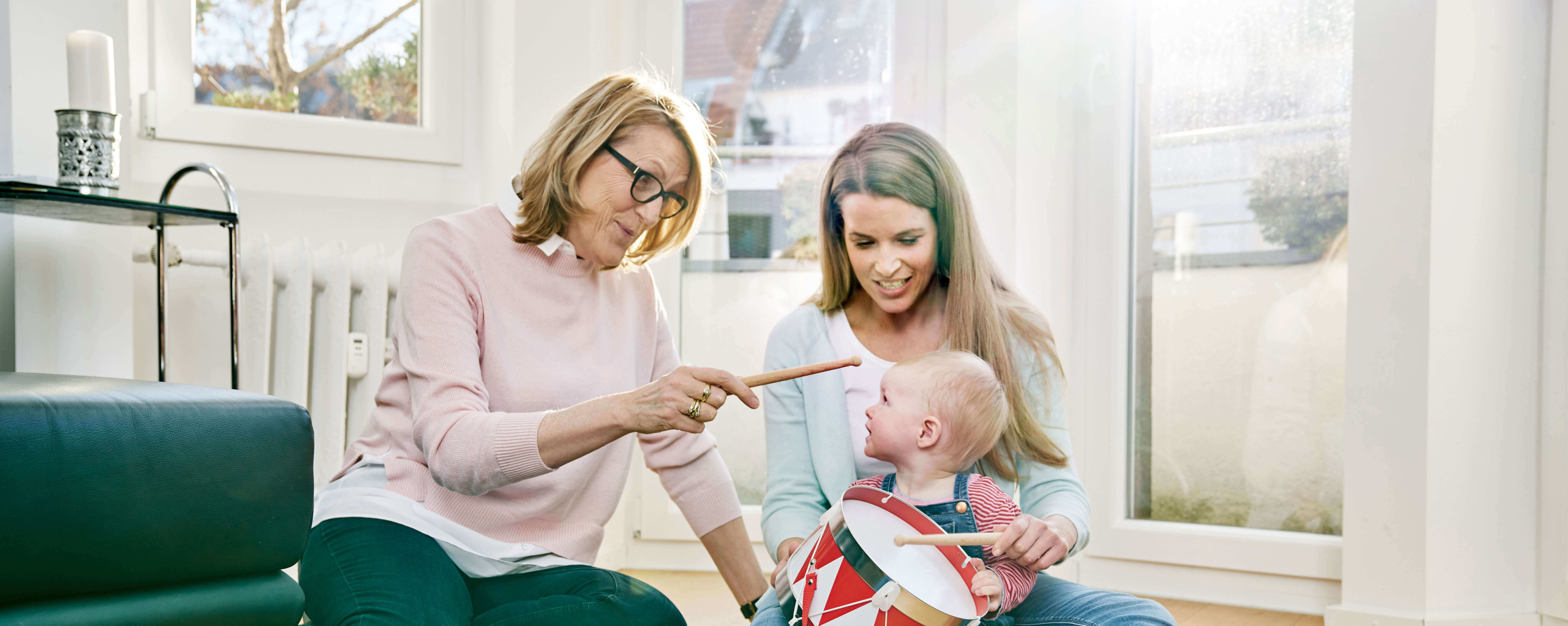 Oma, Mutter und Tochter sitzen auf dem Boden und trommeln.