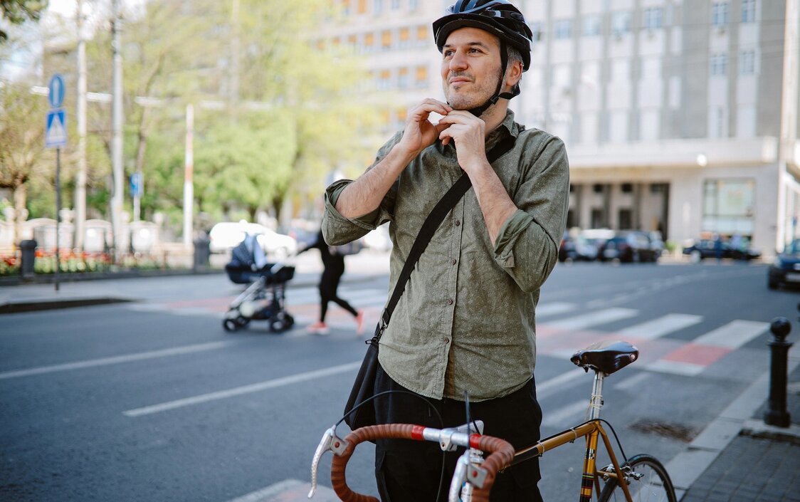 Mann mittleren Alters, der sich für das Fahrradfahren seinen Fahrradhelm festmacht.