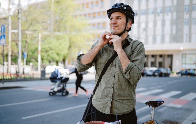 Mann mittleren Alters, der sich für das Fahrradfahren seinen Fahrradhelm festmacht.