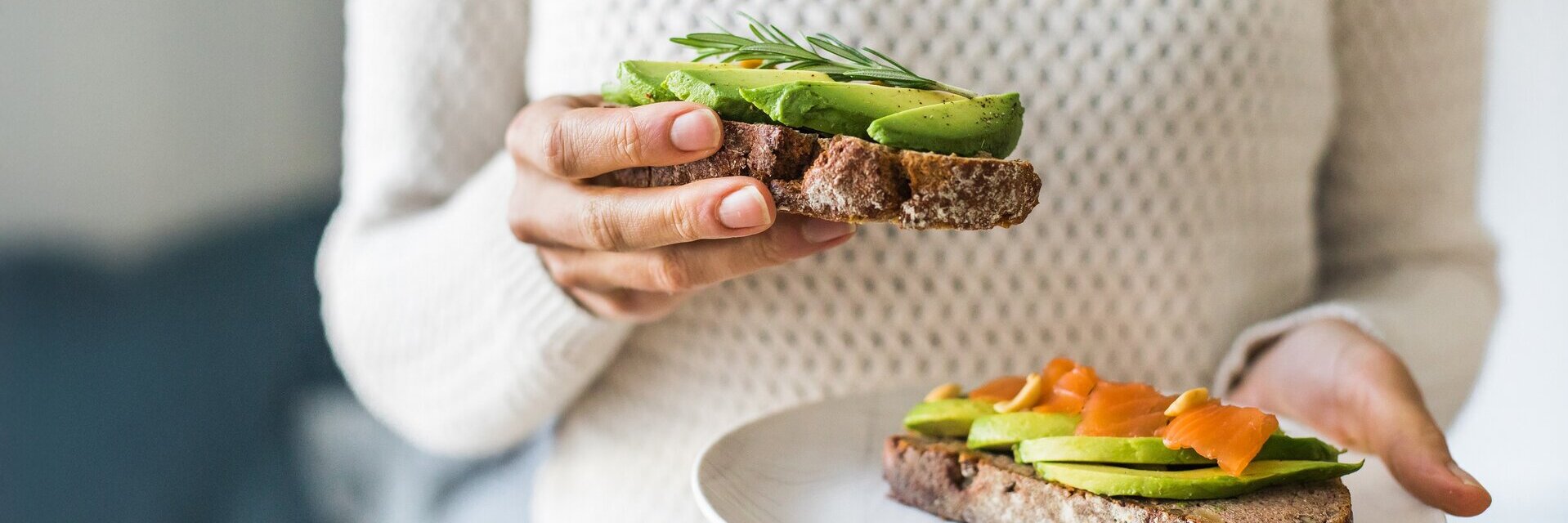 Nahaufnahme der Frau hält Platte mit Avocado-Toast als frischen Snack