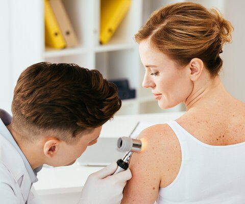 Ein Arzt untersucht die Haut einer Frau.